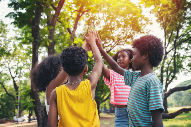 Group of children joining hands together standing in the park, Kids playing teamwork outdoor.